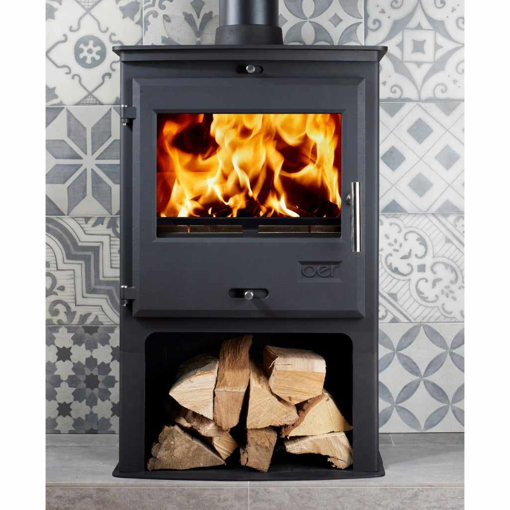 Black OER 5 MultiFuel 5KW stove with a lit fire and log storage, set against patterned grey tiles.