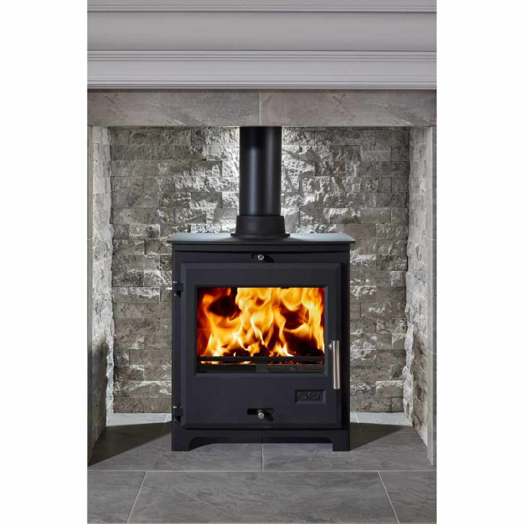 OER 8 MultiFuel stove in black with a burning fire, set in a grey stone fireplace chamber with a black flue pipe.