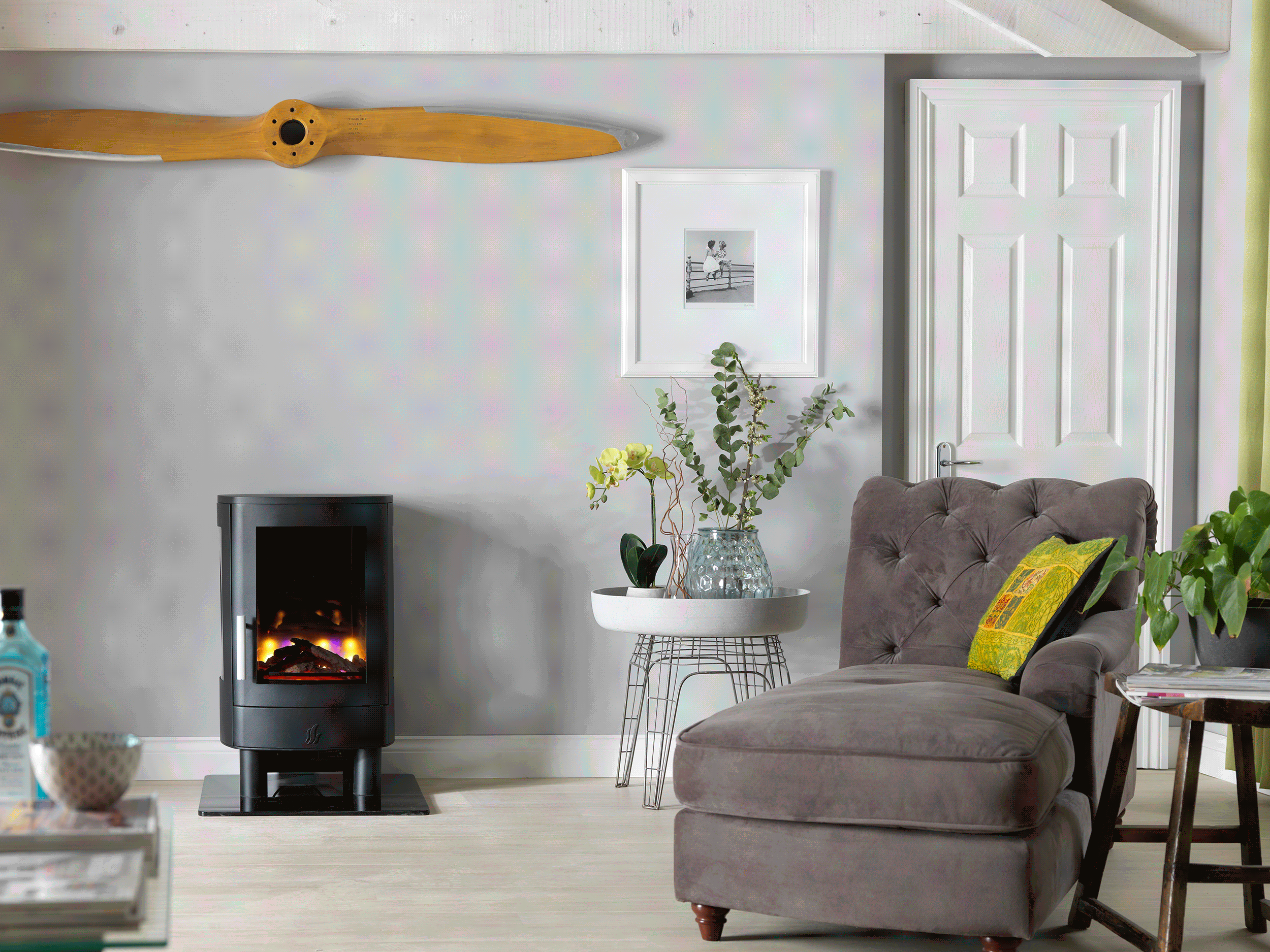 ACR NEO3F electric stove with a black finish and glowing log effect, placed in a modern living room setting.