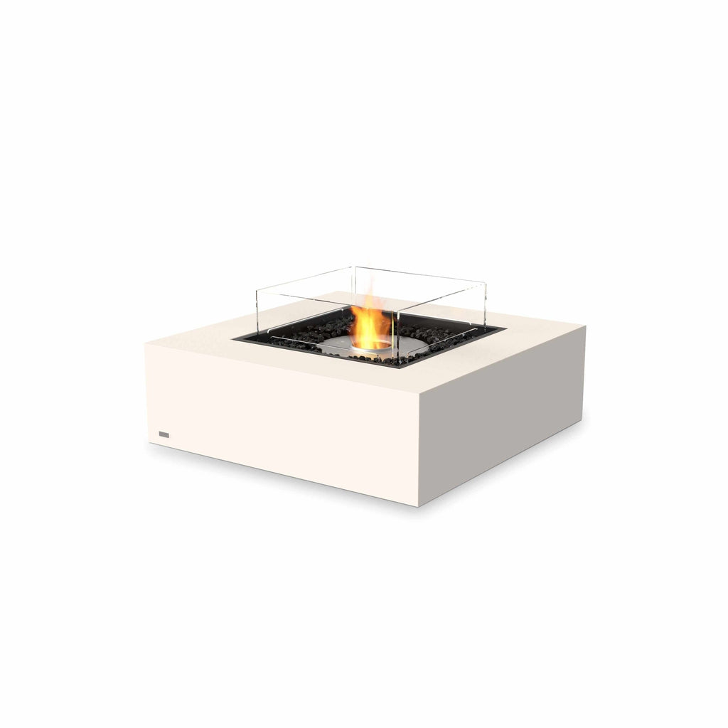 EcoSmart Fire Base 40 bioethanol fire pit table in cream with a square glass screen and central flame on black stones.