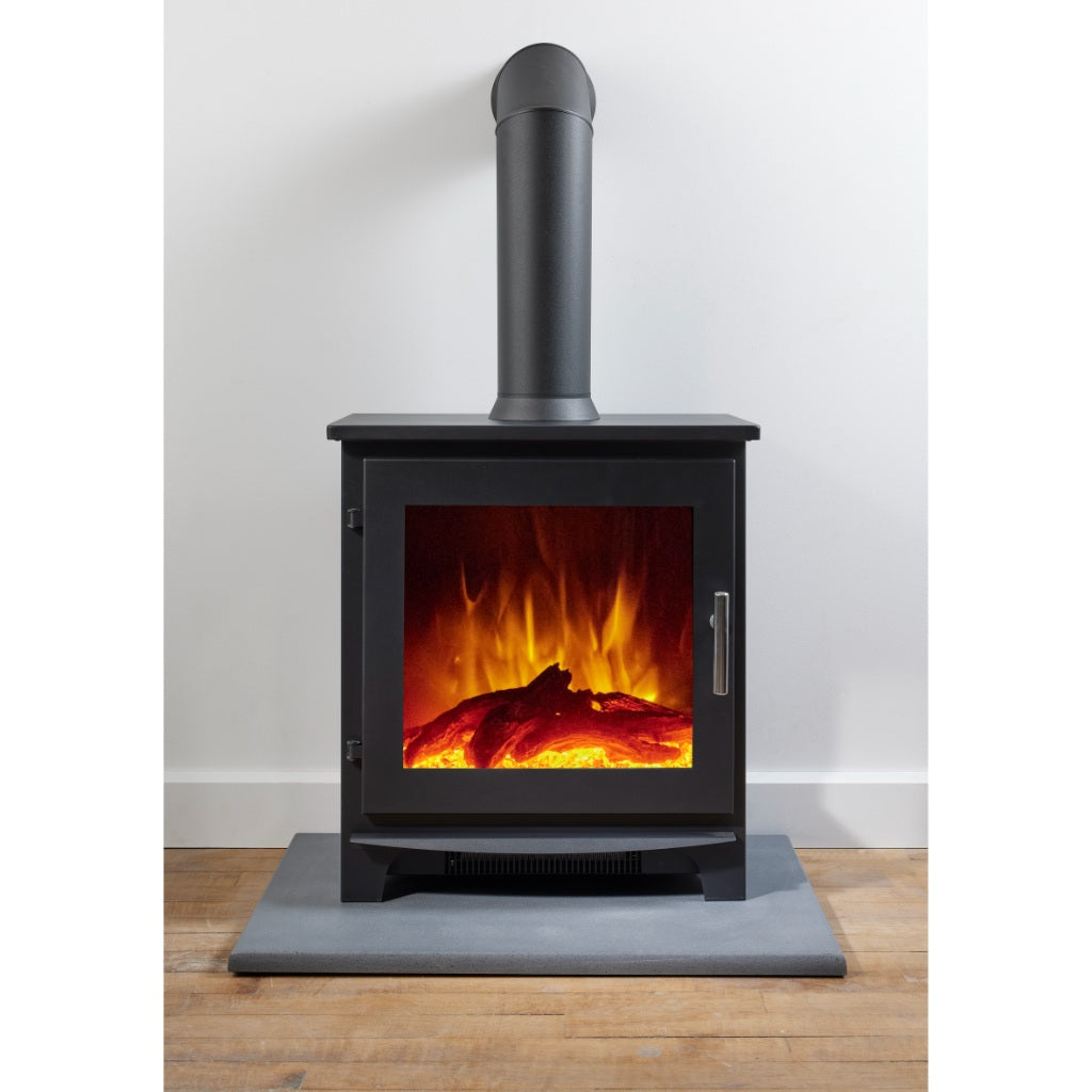 Flametek Trio 3-Sided Electric stove with a black finish, glowing log fuel bed, and vertical flue pipe on a grey hearth.