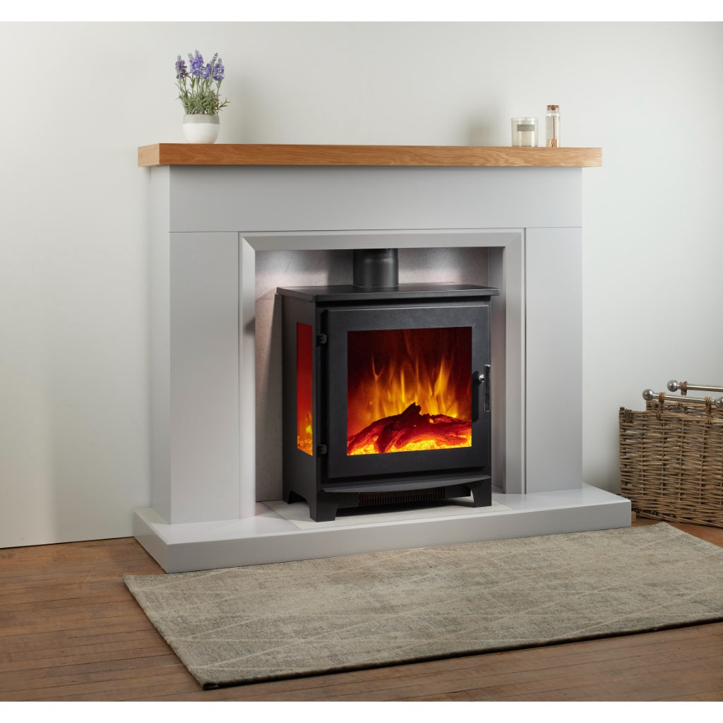 Flametek Trio 3-Sided Electric stove in black, set within a grey fireplace surround with a wooden mantelpiece.