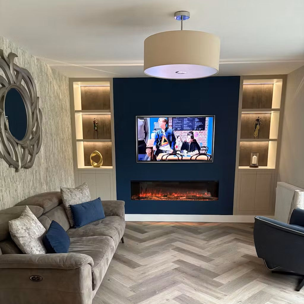 Slimline panoramic electric fire integrated into a navy blue media wall with a mounted TV and illuminated alcove shelving.