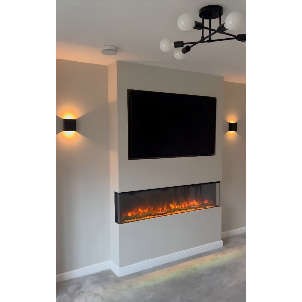 Slimline panoramic 3D electric fire installed in a beige media wall with a mounted TV and warm wall lighting.