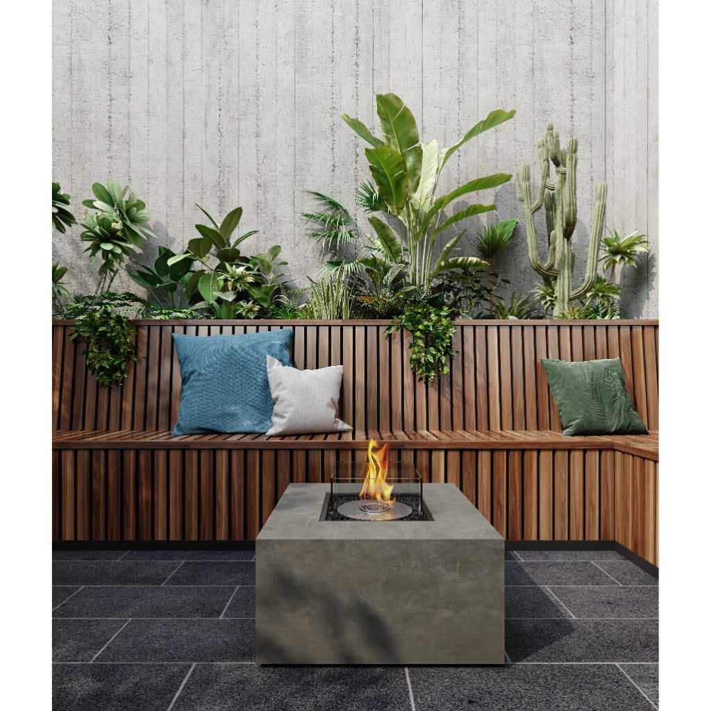 EcoSmart Fire Chaser 38 bioethanol fire pit table in grey concrete on a dark tiled patio with wooden bench seating.