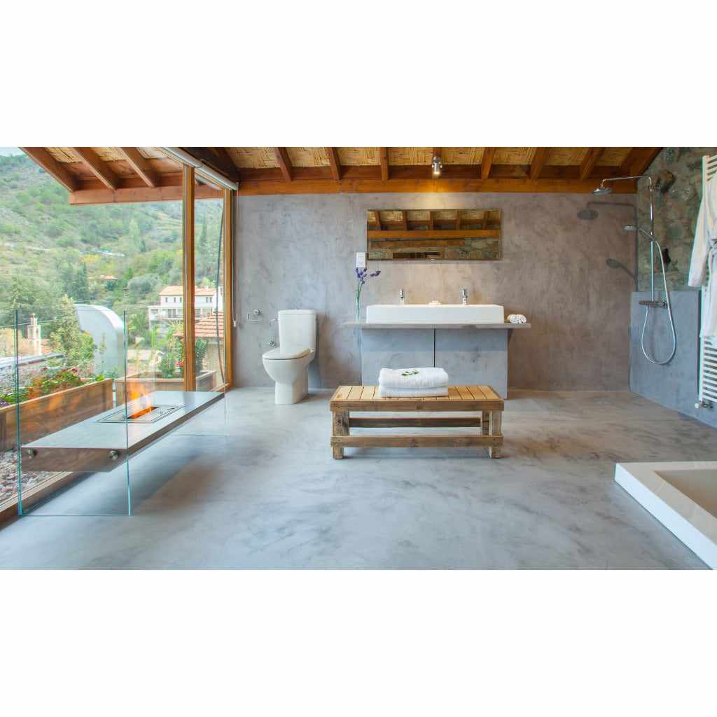 EcoSmart Fire Igloo bioethanol fireplace with a glass surround in a modern bathroom with grey concrete walls.