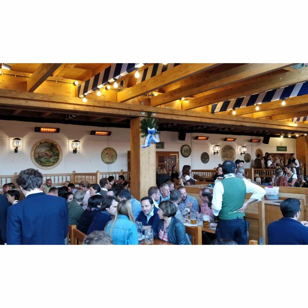 Heatscope Heaters Spot 1600W electric radiant heaters mounted on a white wall in a busy, rustic wooden beer hall.