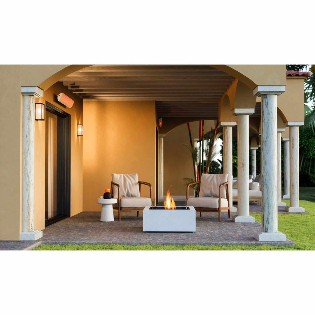 EcoSmart Fire Base 30 bioethanol fire pit table in white, featuring a central flame on a covered stone patio.