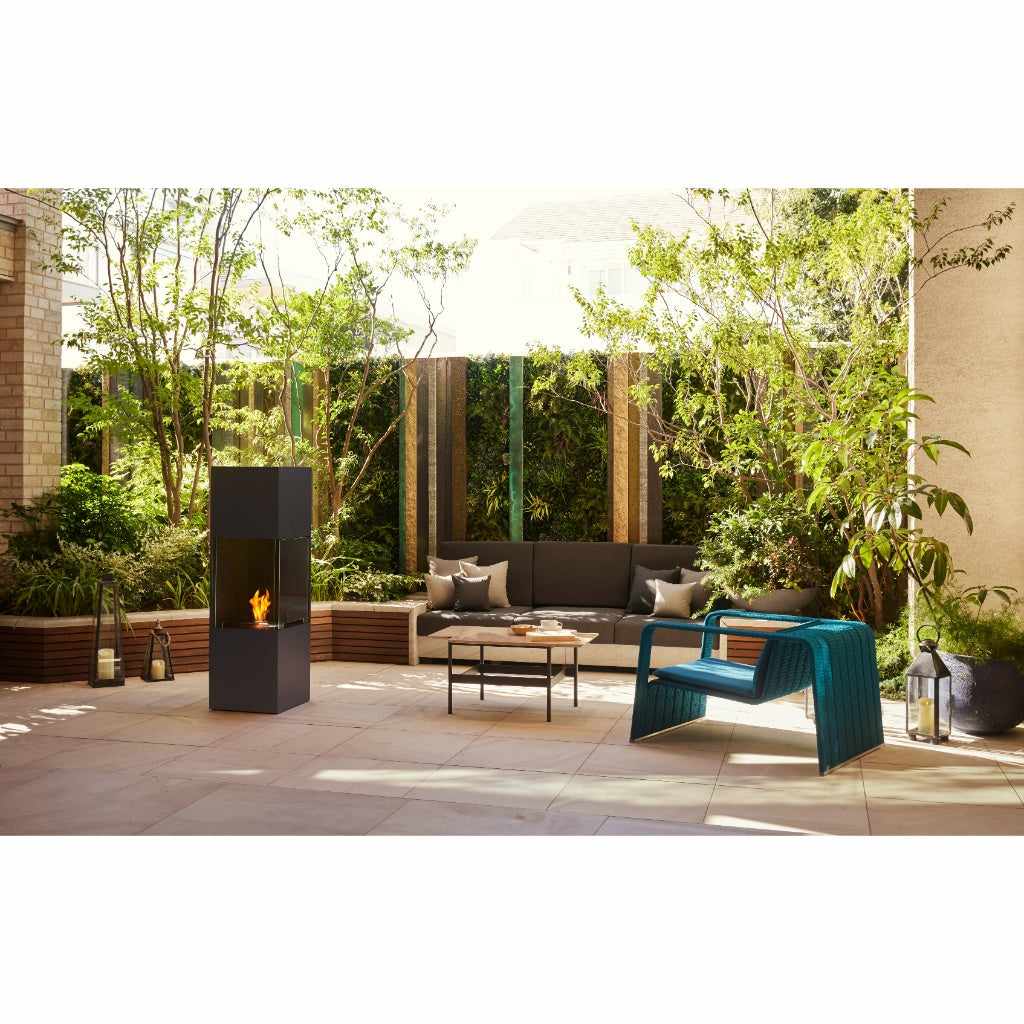 EcoSmart Fire BE Bioethanol Designer Fireplace in a dark grey finish with a visible flame on a modern patio.