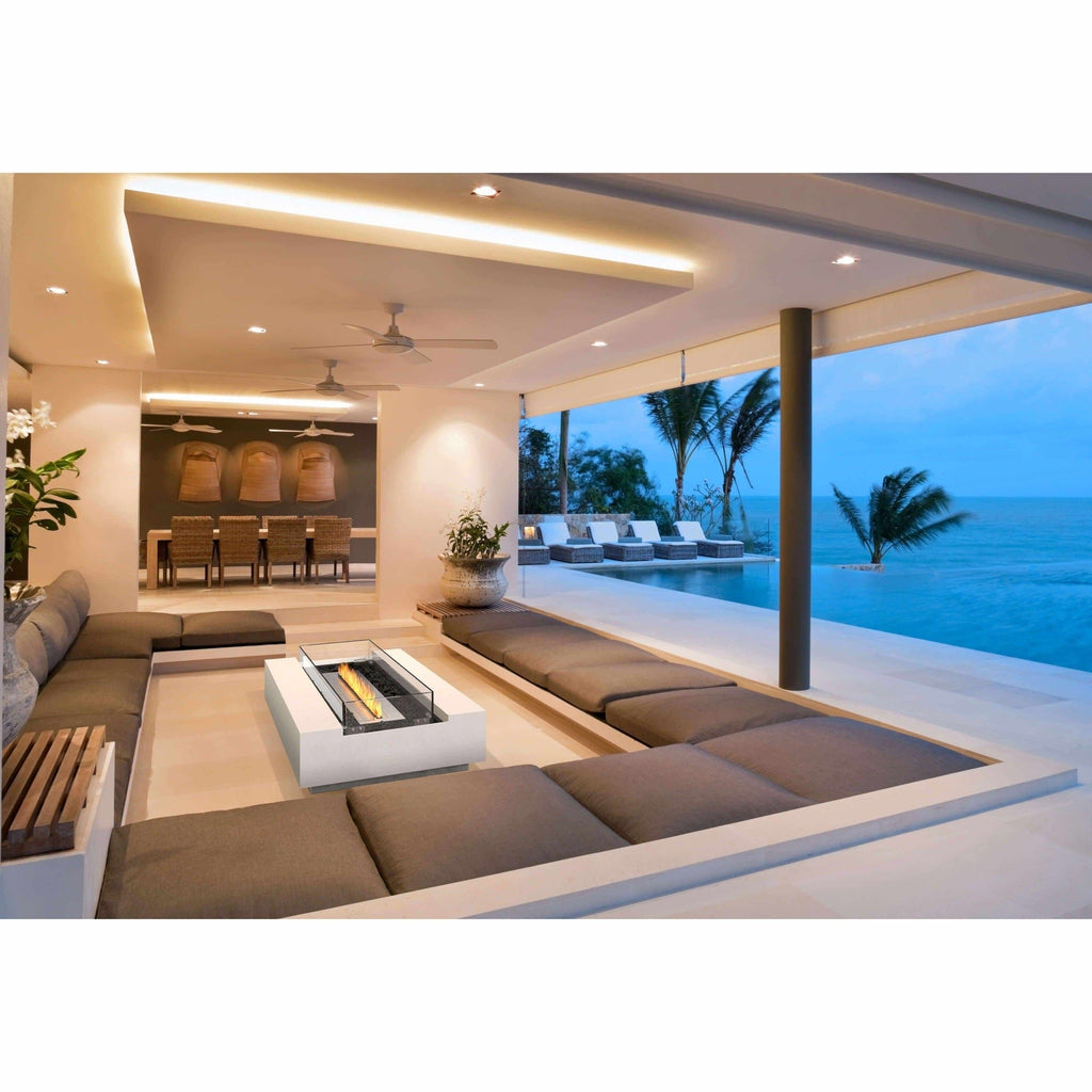 EcoSmart Fire Cosmo 50 bioethanol fire pit table in white, centred in a sunken lounge area overlooking the ocean.