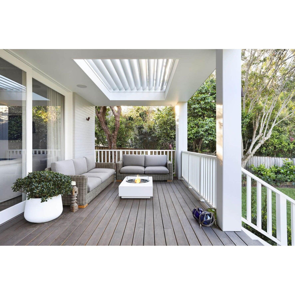 EcoSmart Fire Martini 50 bioethanol fire pit table in white, placed on a wooden deck with grey outdoor sofas.
