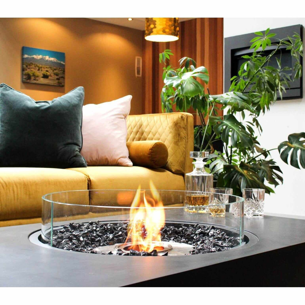 EcoSmart Fire Martini 50 bioethanol fire pit table with black stone, glass surround, and flame in a modern living room.