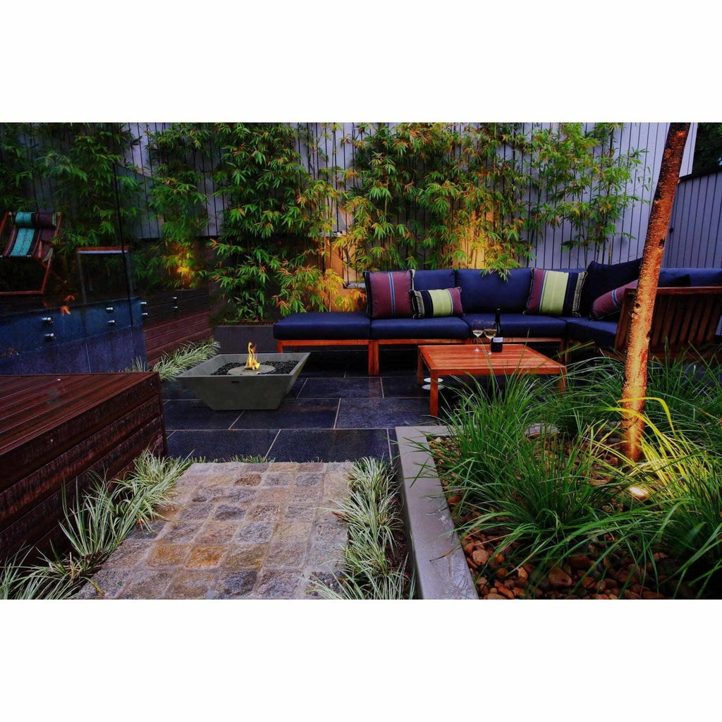 EcoSmart Fire Nova 600 bioethanol fire pit bowl in a grey concrete finish on a dark stone patio in a garden setting.