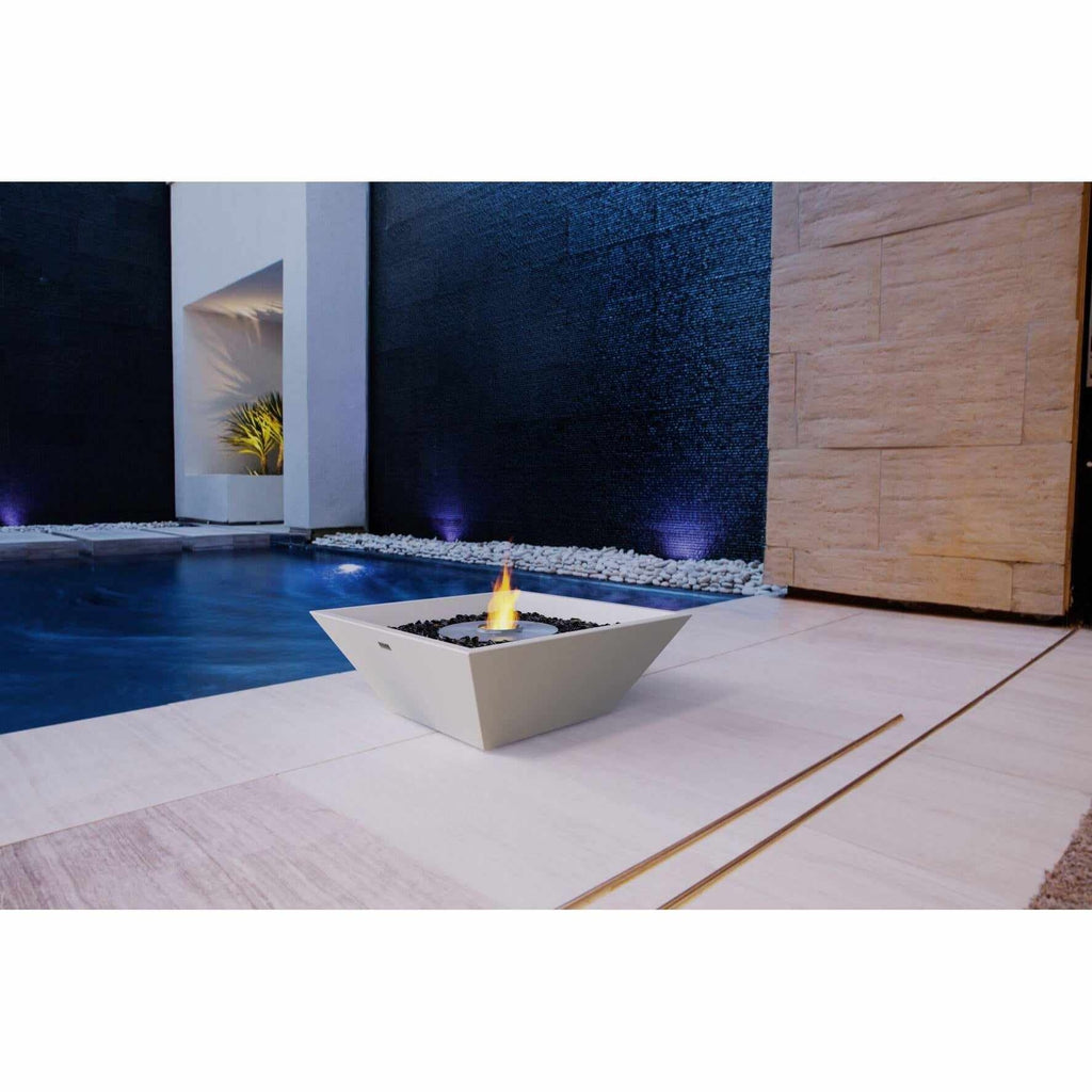 EcoSmart Fire Nova 600 bioethanol fire pit bowl in white, placed on a patio beside a swimming pool at night.