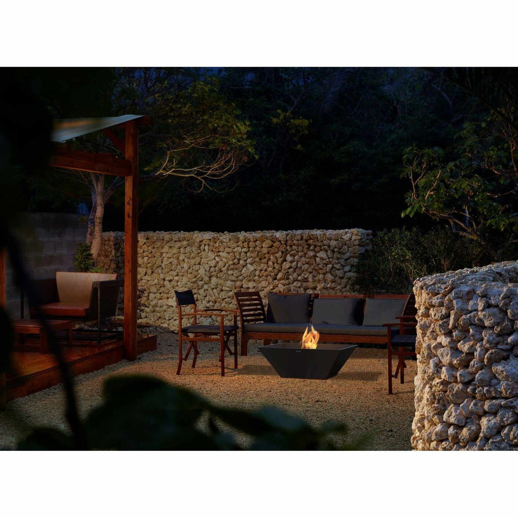 EcoSmart Fire Nova 850 bioethanol fire pit in black, glowing in a garden patio setting at night.