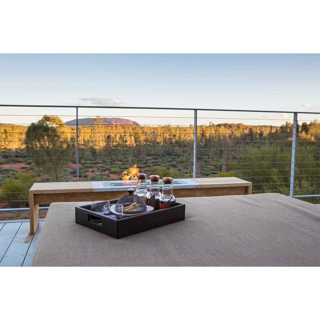 EcoSmart Fire XL700 ethanol burner integrated into a light wood bench on an outdoor deck overlooking a desert landscape.