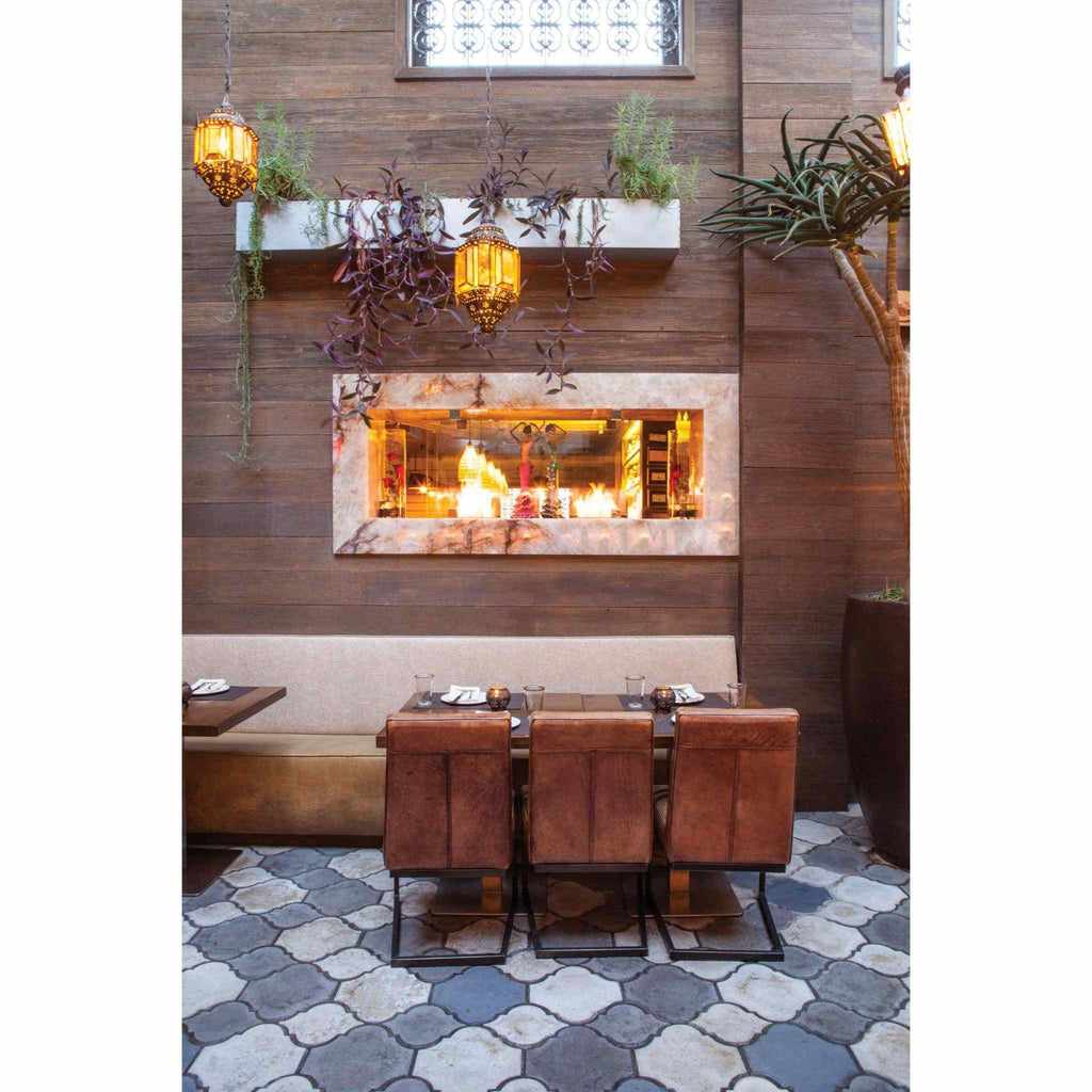 EcoSmart Fire XS340 ethanol burner inset into a stone-framed wall above a restaurant dining table with leather chairs.
